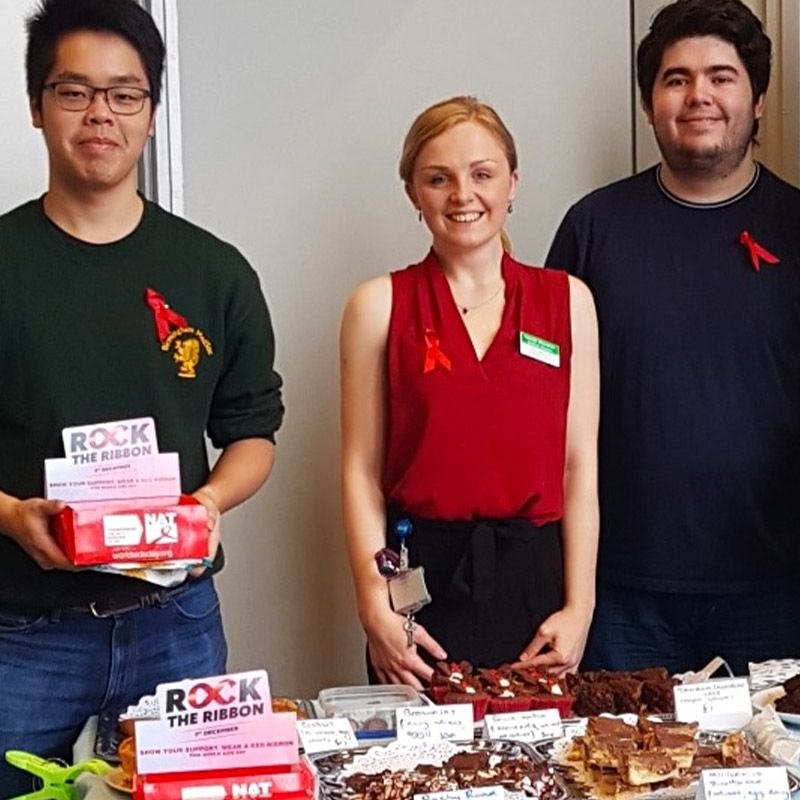 3 people at a bake sale raising money for World AIDS Day
